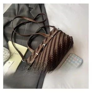 Detail shot of a dark brown pleated Boston bag with soft textures and metallic buckles