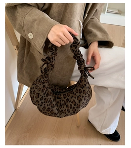 Close-up of leopard print crescent bag featuring ruched handles and a delicate bow detail