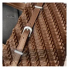 Detail of dark brown pleated texture on tote bag with silver buckle and fine stitching