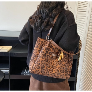 Detailed view of leopard print tote bag with brown leather straps and beaded charm