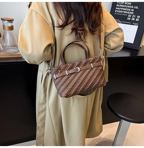 Detail of brown Boston bag with textured weave and metal buckle on khaki trench coat