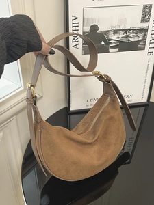 Braune Wildleder-Hobotasche mit Lederriemen und Gold-Hardware in urbanem Ambiente