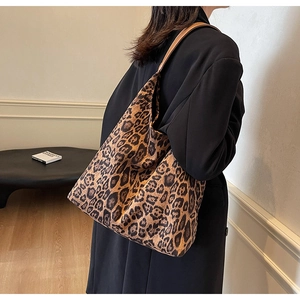 Detailed shot of leopard print tote bag with brown leather handles worn over the shoulder