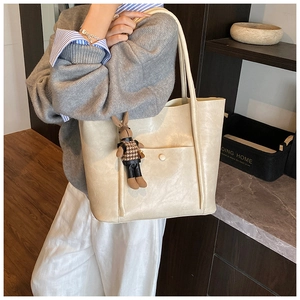 Off-white tote bag with crossbody strap and cute bunny charm shown on a female model