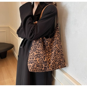Fashionable large leopard print tote bag with brown leather strap shown on model's shoulder