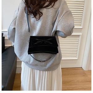Gros plan d'un sac bandoulière noir élégant avec un grand nœud décoratif et une chaîne