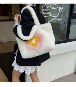 Detailansicht der großen weißen Plüschtasche mit Sonnenblume an der Schulter des Models