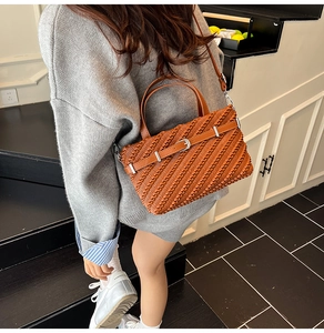 Detail of a brown woven Boston bag featuring leather straps and silver buckle finish