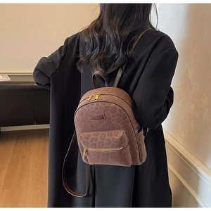 Détail d'un sac à dos imprimé léopard montrant la texture en daim et les zips dorés