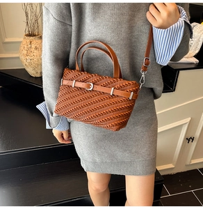 Close-up of brown woven texture Boston bag with silver buckle and adjustable strap