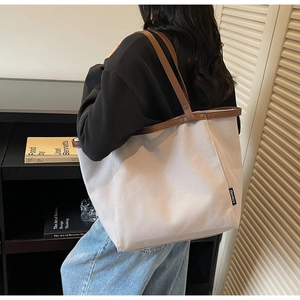 Detail of the gray canvas tote bag featuring premium brown leather straps and stitching