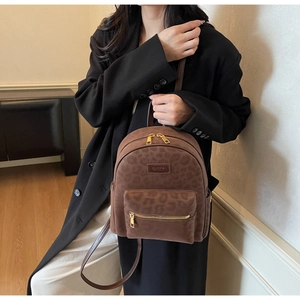 Détail d'un sac à dos tendance à imprimé léopard avec fermetures éclair dorées et logo