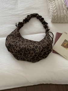 Chic leopard print half-moon tote bag with scrunchie shoulder strap in a cozy setup