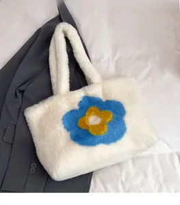 Detail der weißen Kunstfell-Einkaufstasche mit Sonnenblumen-Motiv auf grauem Blazer