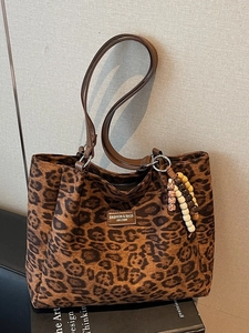 Classic leopard print tote bag with brown leather handles and ethnic bead accessory
