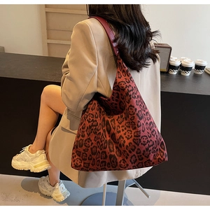 Detail of red and black leopard print tote bag with wide strap on a cafe table