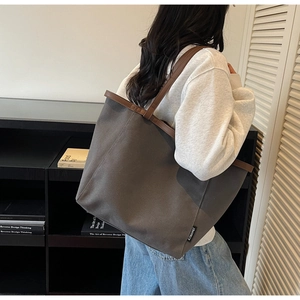 Detail view of large taupe canvas tote bag with brown faux leather straps and side label