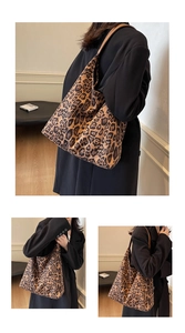 Detail view of large leopard print tote bag featuring brown leather shoulder straps