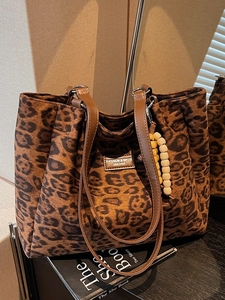Chic leopard print tote bag with brown leather handles and a beaded tassel charm