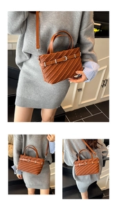 Close-up of brown woven Boston bag with silver buckle and adjustable shoulder strap