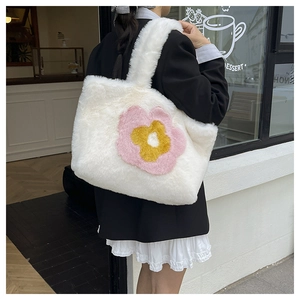Detail der weißen Plüschtasche mit Sonnenblumen-Stickerei und weicher Pelzstruktur