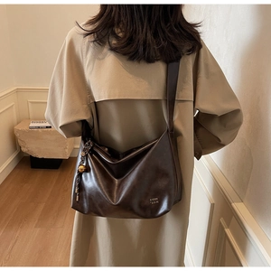 Détail d'un grand sac fourre-tout en cuir marron foncé avec pendentif métallique