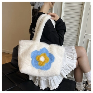 Detailaufnahme der weißen Plüschtasche mit gelb-blauen Sonnenblumen-Stickereien