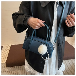 Blue suede bowling bag with fluffy pom-pom and pearl chain details shown with a model