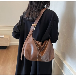 Détail d'un grand sac hobo en cuir marron vintage avec boucle dorée et bandoulière