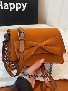 Sac à bandoulière marron caramel avec nœud décoratif, chaîne argentée et rabat chic