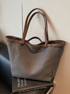 Minimalist dark gray canvas tote bag with brown leather handles on a home decor background