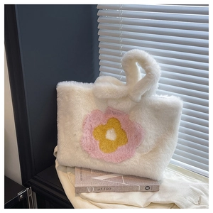 Detail einer weichen weißen Plüschtasche mit bunten Sonnenblumen-Applikationen