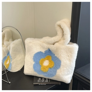 Detail der weißen Kunstpelz-Tragetasche mit Sonnenblumen-Motiv neben einem Schminkspiegel