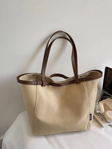 Large beige canvas tote bag with brown straps and laptop for minimalist daily use