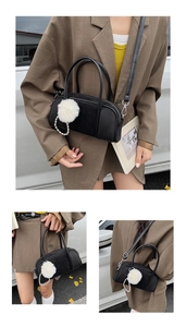 Detail of black suede bowling bag with white pompom and pearl chain strap on model