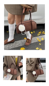Detail of brown suede bowling bag with white fur pompom and pearl chain accessories