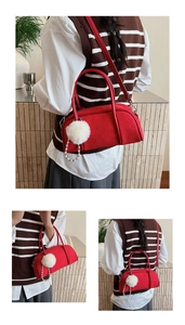 Detailed close-up of red suede baguette bag with pearl chain and white plush ball charm