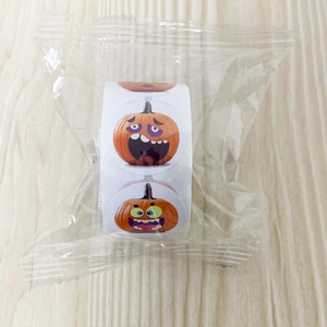 Detail of Halloween pumpkin face stickers roll in plastic packaging on a wood background