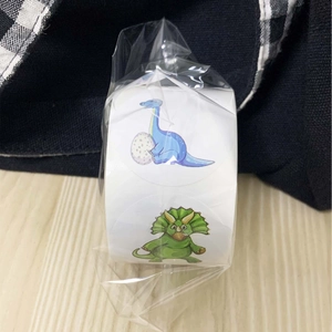 Cartoon dinosaur roll stickers for kids rewards on a light wood background