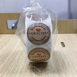 Detail of round kraft stickers with red hearts and Spanish text in clear packaging