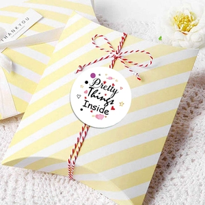 Round white sticker with Pretty Things Inside text on striped gift box with dry flowers