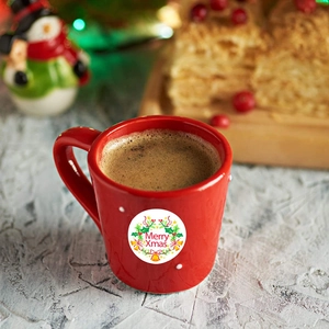 Christmas Merry Xmas round stickers with holly leaves and bells on a red coffee cup