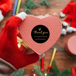 Autocollants noirs ronds dorés Thank You sur boîte cadeau avec décor de fête