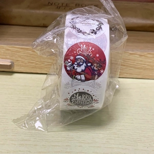 Detailed view of rolled Christmas adhesive stickers in plastic wrap on a wooden desk