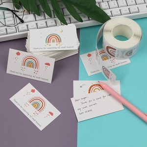 Macro shot of rainbow-themed business thank you cards and matching sticker roll on a desk