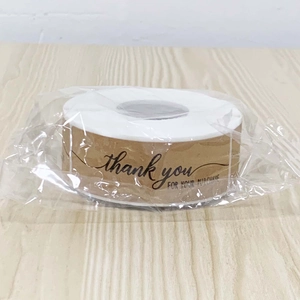 Close-up of thank you kraft paper stickers roll in transparent protective shrink wrap