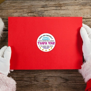 Autocollants de remerciement arc-en-ciel sur carte rouge tenue par le père Noël