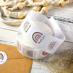 Macro detail of rainbow Thank You stickers roll on rustic white wood with boho decor