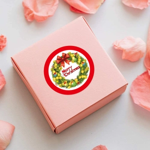 Close-up of a pink gift box featuring a round Merry Christmas sticker with green wreath