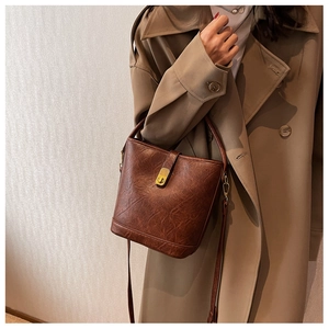 Detail of a brown vintage leather bucket bag with gold lock and adjustable shoulder strap